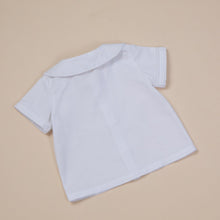 Load image into Gallery viewer, white cotton short sleeve top with peter pan collar and piping for baby boy or toddler boy on beige background.