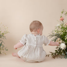 Load image into Gallery viewer, a natural flax linen onesie with white trim detail for baby girl or toddler girl on beige background