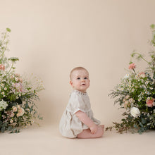 Load image into Gallery viewer, a natural flax linen onesie with white trim detail for baby girl or toddler girl on beige background