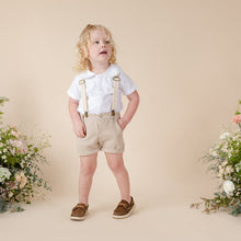 Load image into Gallery viewer, Beige cotton shorts with suspenders, faux fly and two pockets for baby boy or toddler boy on beige background.
