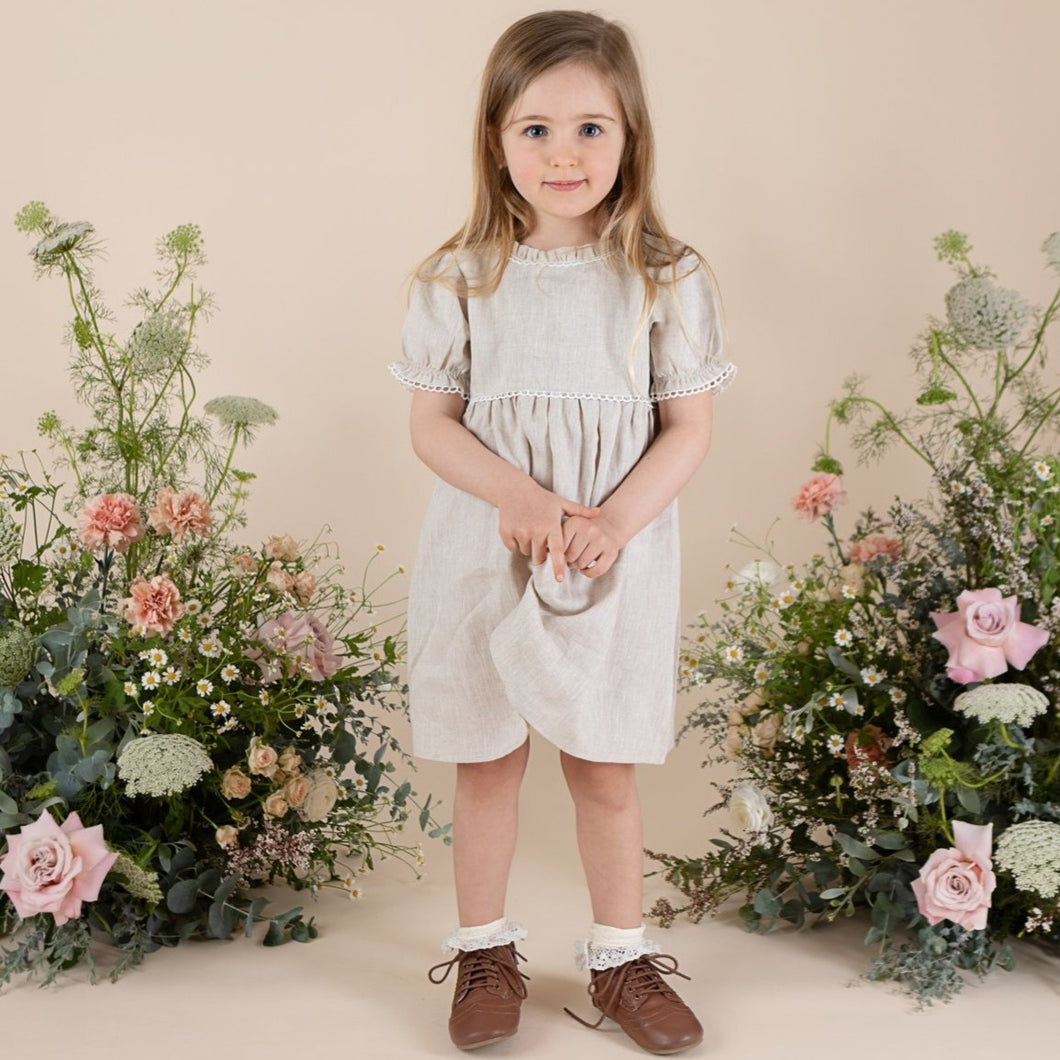 a young girl in natural colour 100% linen day dress cut above the knee with puffy short sleeve