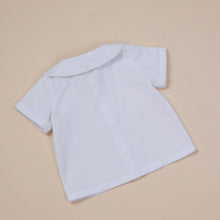 Load image into Gallery viewer, white cotton short sleeve top with peter pan collar and piping for baby boy or toddler boy on beige background.

