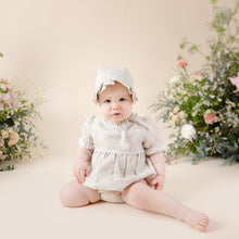 Load image into Gallery viewer, a natural flax linen onesie with white trim detail for baby girl or toddler girl on beige background
