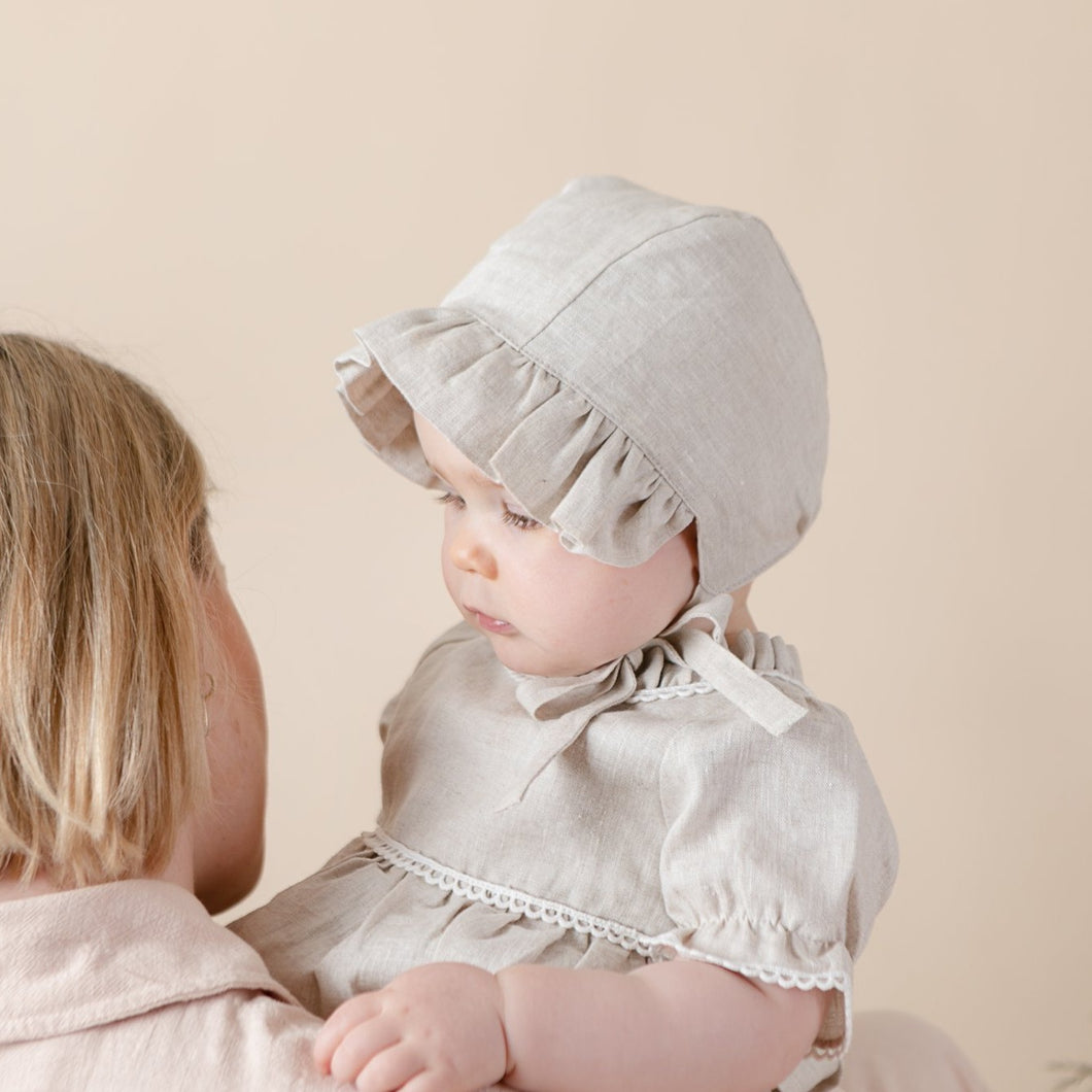 natural flax linen bonnet for baby girl on beige background